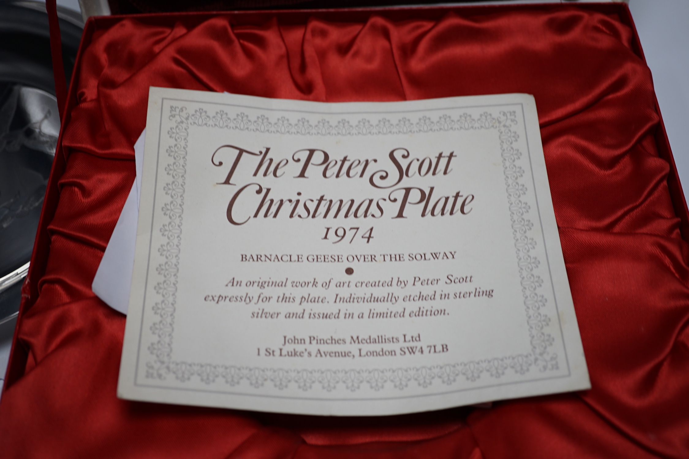 A boxed silver Peter Scott Christmas plate, 1974, depicting etched birds in flight, John Pinches, London 1974. Diameter 20.5cm, 5.9oz.